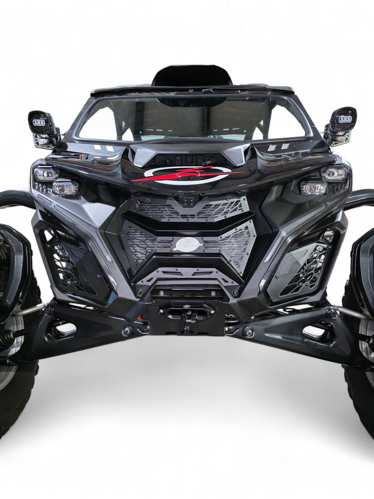 2024 Can-Am Maverick R fitted with Volt 3-Piece Grille in hammer black powder coat
    finish, full front view on a desert trail showing contour-matched fitment and
    billet aluminum badge detail
