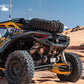 Rear Volt Bumper mounted on Can-Am Maverick R 2-Door viewed from driver's side rear quarter angle in a desert dune setting with hammer black powder coat finish