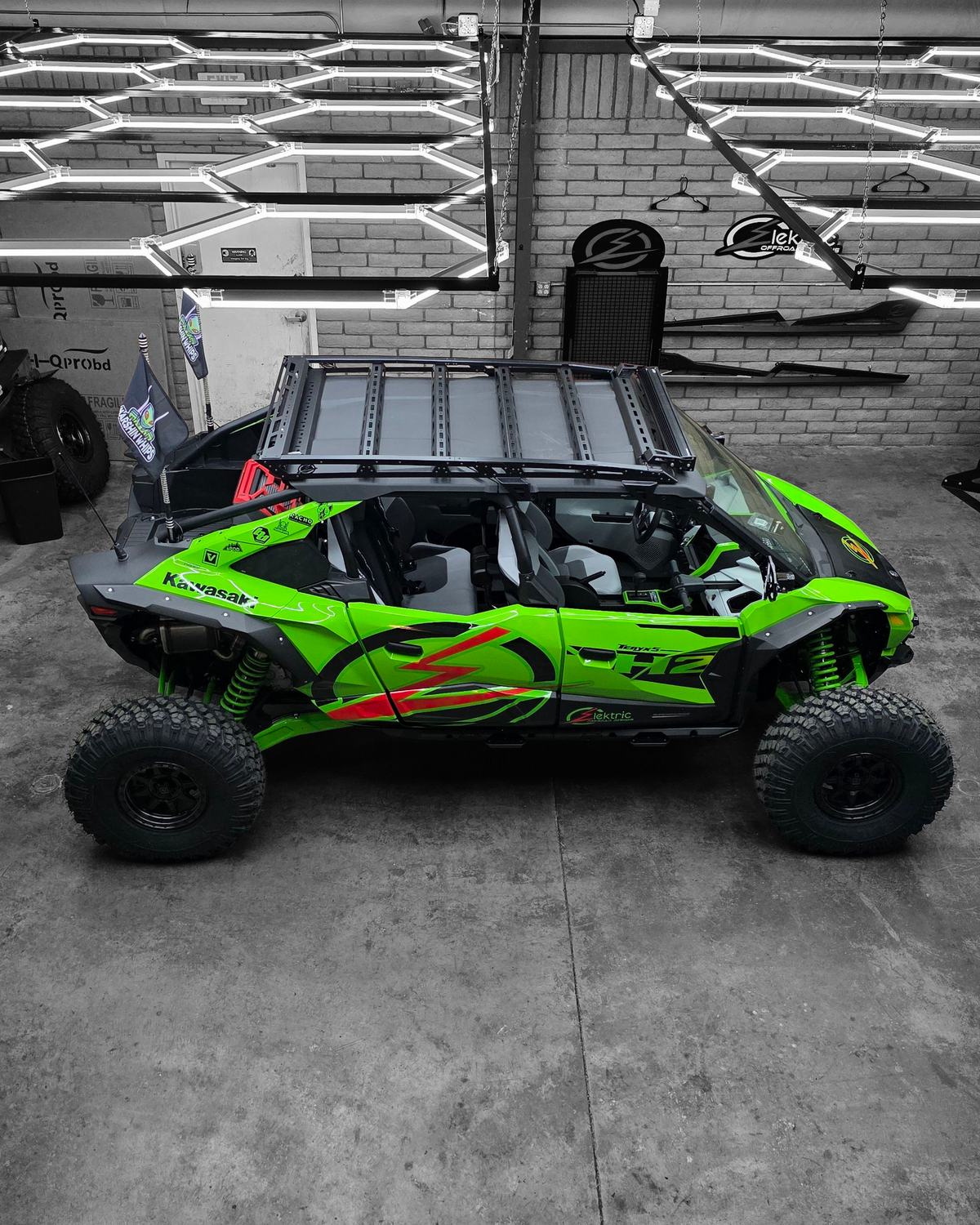 Green off-road vehicle with large tires in a garage setting