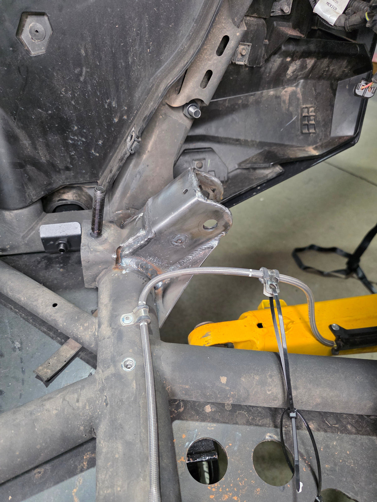 Can-Am Maverick R trailing arm pivot gusset shown next to factory mount for comparison