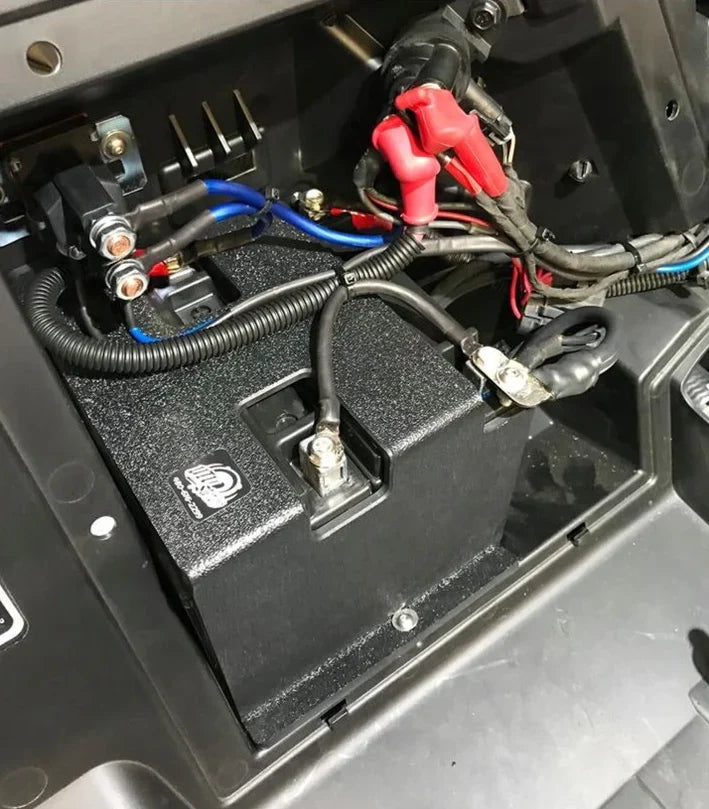 Black battery housing with connected cables and terminals installed in a vehicle compartment