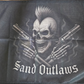 Flag with a skull holding guns and 'Sand Outlaws' text on a dark background