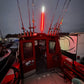 Red fishing boat interior with a lit red light against a dark sky.