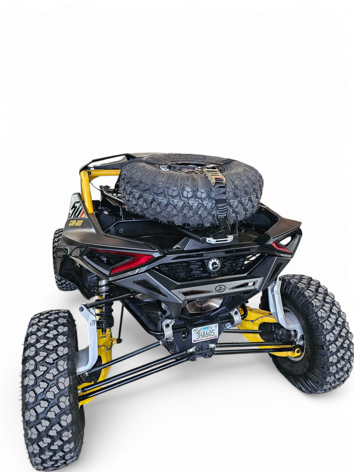 35-inch spare tire securely mounted on Can-Am Maverick R EOD Volt 
Tire Rack with Y straps holding tire in position