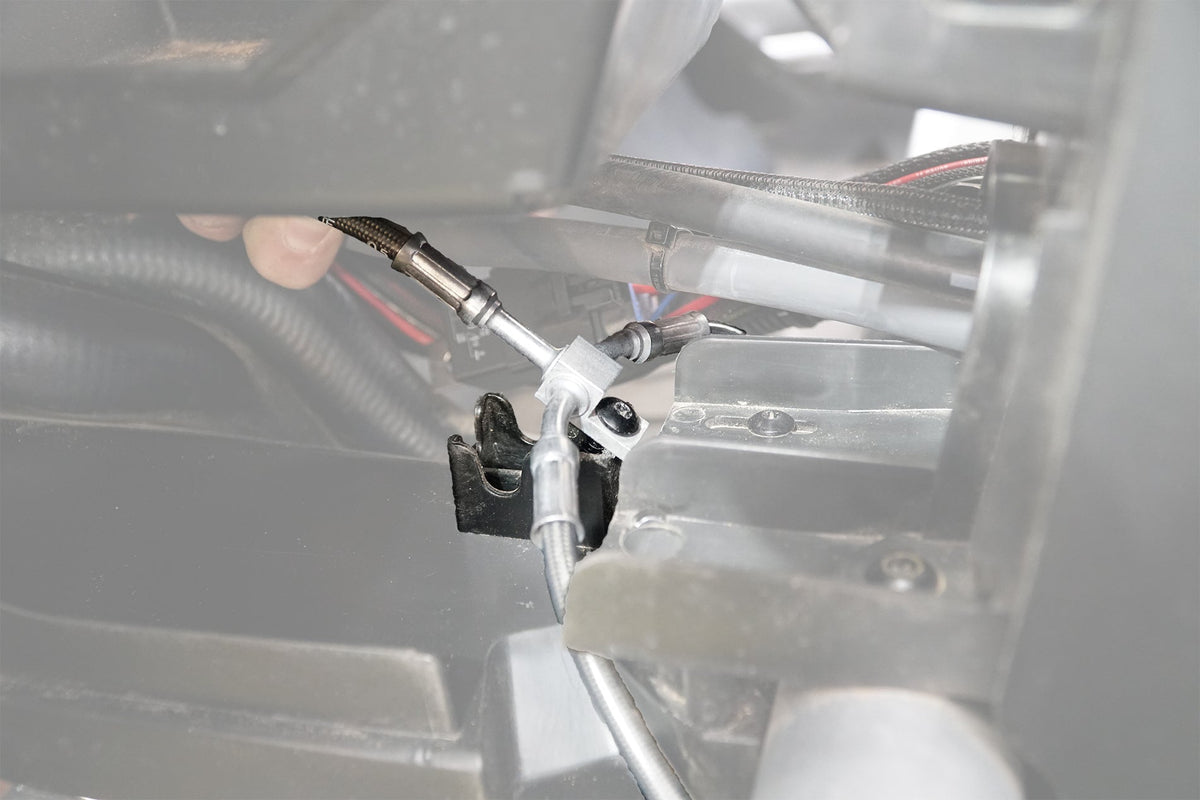 Close up of a metal brake line splitter block installed on a vehicle frame