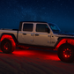 Jeep Gladiator truck on a beach at night with red underglow lights