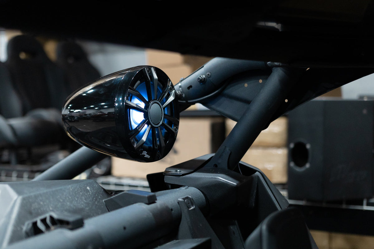 UTV Stereo black pod speaker with blue LED lighting mounted on a vehicle roll cage