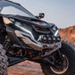 A front winch bumper designed for a Can Am Maverick R, featuring a black powder coat finish and integrated LED light bar, mounted on a off-road vehicle.
