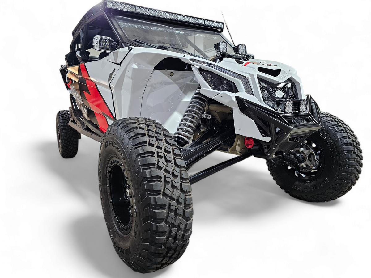 Black anodized Can-Am Maverick X3 billet front winch bumper with round lights mounted showing forward lighting setup