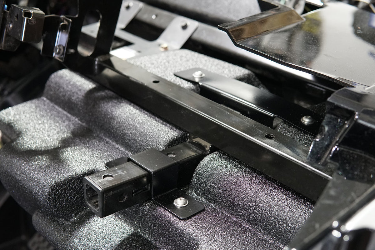 Black metal trailer hitch receiver mounted on textured vehicle chassis
