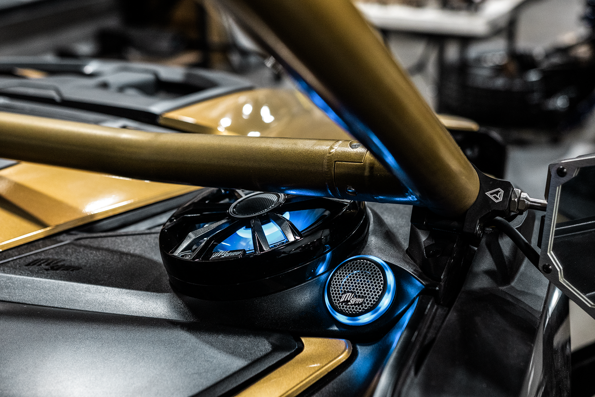 MTX Audio speakers with blue LED lighting mounted on a gold roll cage of an off road vehicle