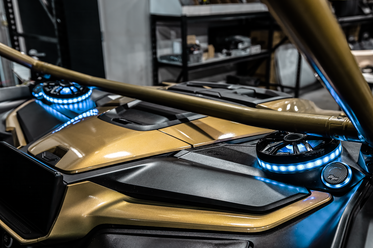 UTV Stereo speakers with blue LED rings installed in a gold off-road vehicle dashboard