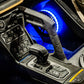 Center console of a vehicle with gear shifter, start button, and illuminated blue speaker