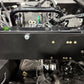 Black metal mounting plate installed on vehicle chassis with visible bolts and wiring harness