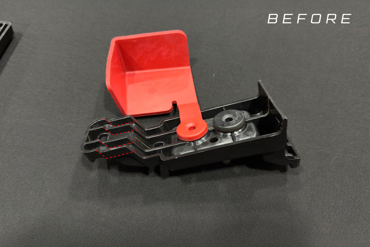 Black plastic automotive component with red cover and red dashed line indicating area for modification