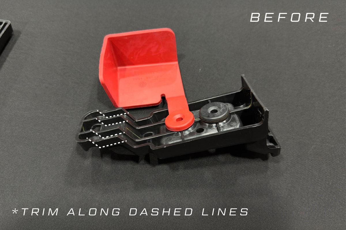 Black and red plastic automotive part with white dashed lines indicating where to trim